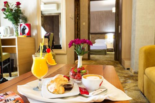 a table with a plate of food and a glass of orange juice at Balneo Complex & Spa Aquatonik in Velingrad