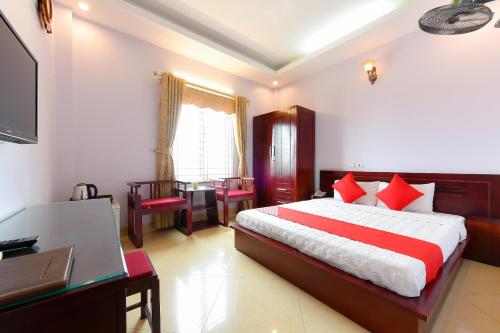 a bedroom with a bed with red pillows and a desk at TITANIC HOTEL in Hanoi