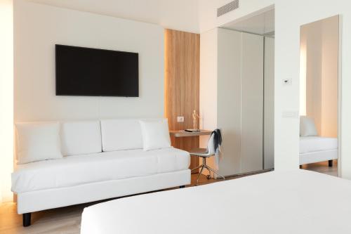 a hotel room with a white bed and a mirror at Toscana Charme Resort in Tirrenia