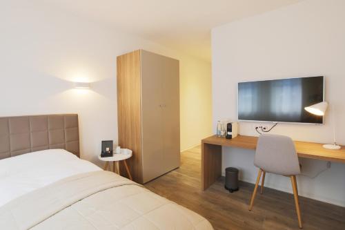 a bedroom with a bed and a desk with a television at Hotel Work Life Residence am Bahnhof in Winterthur