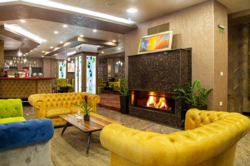 a lobby with yellow furniture and a fireplace at Balneo Complex & Spa Aquatonik in Velingrad