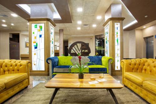 a living room with yellow and blue couches and a table at Balneo Complex & Spa Aquatonik in Velingrad