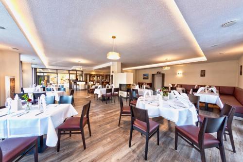 uma sala de jantar com mesas e cadeiras brancas em Restaurant und Hotel Knostmann em Hunteburg