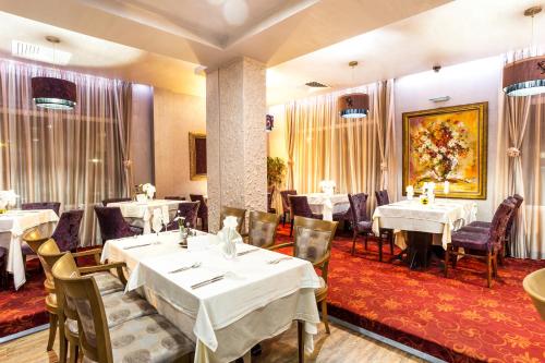a restaurant with white tables and chairs and a painting at Balneo Complex & Spa Aquatonik in Velingrad