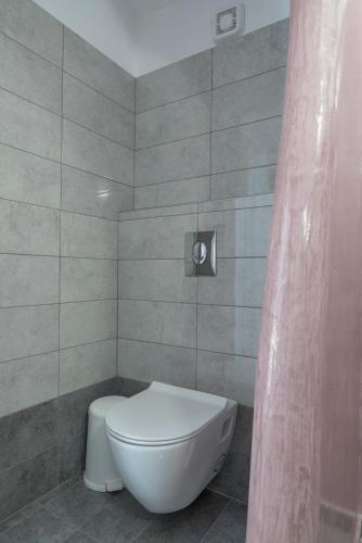 a bathroom with a white toilet and a shower curtain at Margarita in Perissa