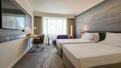 a hotel room with two beds and a desk at Novotel Kuala Lumpur City Centre in Kuala Lumpur