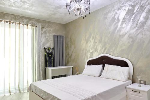 sypialnia z dużym białym łóżkiem z żyrandolem w obiekcie Deluxe Apartment Spa n Pools Beach resort w mieście Năvodari