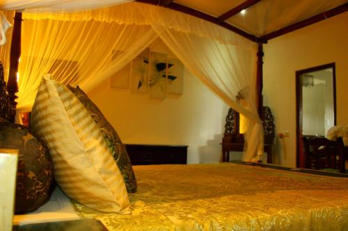 a bedroom with a canopy bed with pillows at Asian Jewel Boutique Hotel in Hikkaduwa