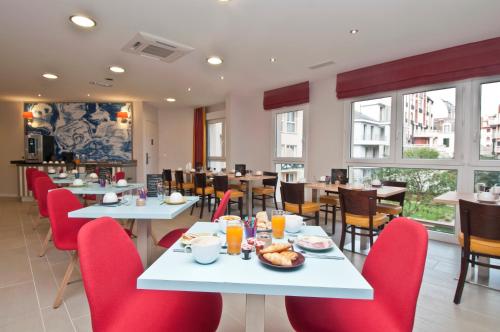 a dining room with tables and red chairs at Résidence Pierre & Vacances Premium Haguna in Biarritz