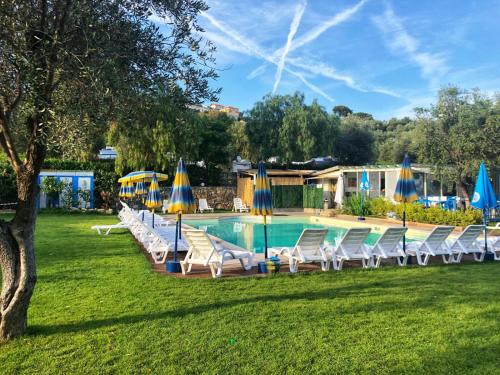 a swimming pool with chairs and umbrellas at Camper Village in Santo Stefano al Mare
