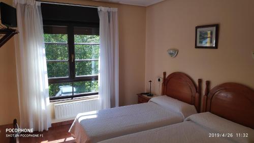 1 dormitorio con 2 camas y ventana en Hotel Benzua, en Villanueva de Ardisana