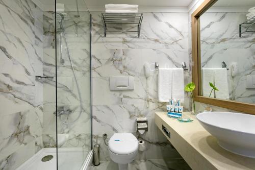 y baño con aseo, lavabo y ducha. en Innvista Hotels Belek en Belek