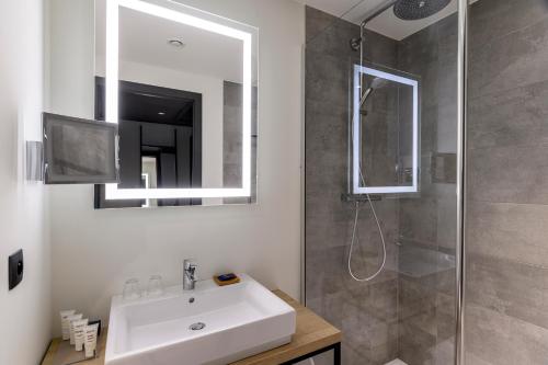 a bathroom with a sink and a shower with a mirror at Radisson Hotel Antwerp Berchem in Antwerp