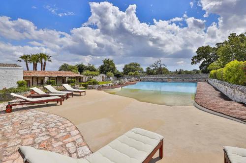 a swimming pool with lounge chairs next to a stone wall at Masseria Casina Vitale in Ceglie Messapica