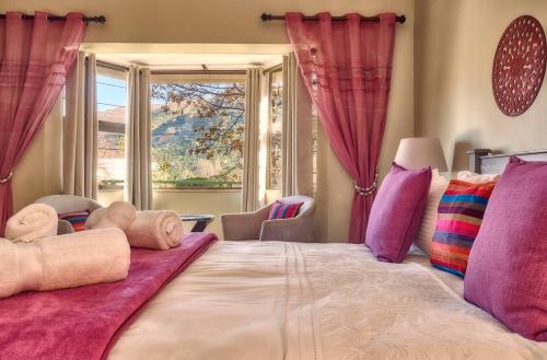 sypialnia z dużym łóżkiem z różowymi i fioletowymi poduszkami w obiekcie Golden View - Oak on Church w mieście Clarens