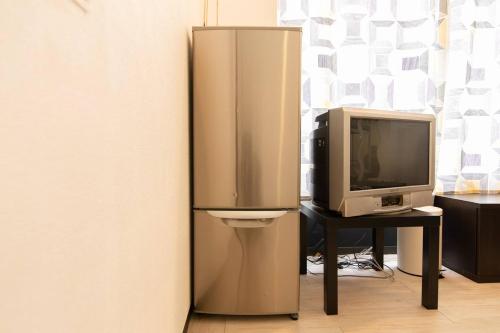 a refrigerator next to a desk with a tv at Chiba Green hills Inage #8Mx in Chiba