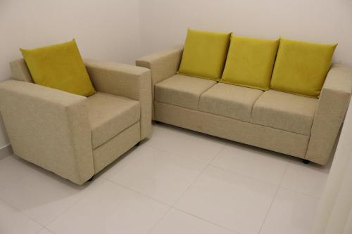 two chairs and a couch with yellow cushions in a room at Hill Country Villa in Kandy