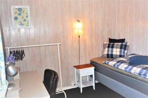 een kleine kamer met een bed, een tafel en een lamp bij Løvheim Gjestehus - Anneks in Sauland
