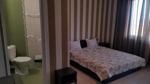 a small bedroom with a bed and a toilet at На гости при Силвия in Obzor