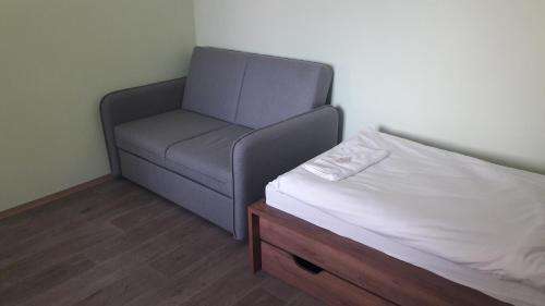 a bed and a chair in a room at Penzion Rozhovice in Rozhovice