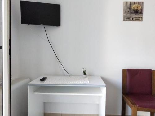 een wit bureau met een toetsenbord en een tv aan de muur bij La Santera in Marina di Davoli