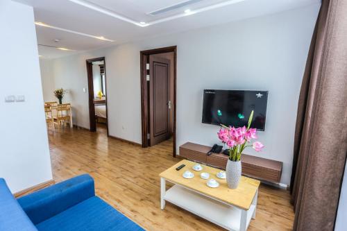 a living room with a blue couch and a table with flowers at HNC Premier Hotel & Residences in Hanoi