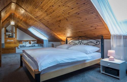 a bedroom with a large bed with a wooden ceiling at Apartments - BOWLINGHORKA sk in Poprad