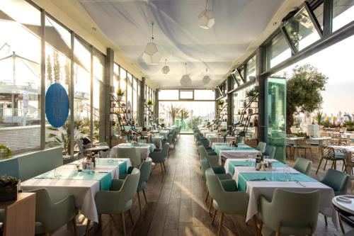 a restaurant with tables and chairs and windows at Hotel Opera Mamaia in Mamaia