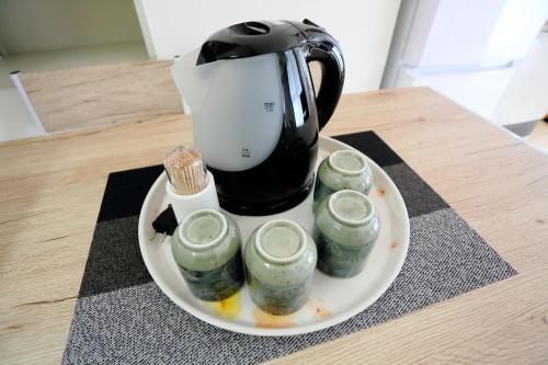 a coffee pot on a plate with four green candles at Near Nakajima park Close to Susukino Anbiennte 101 in Sapporo