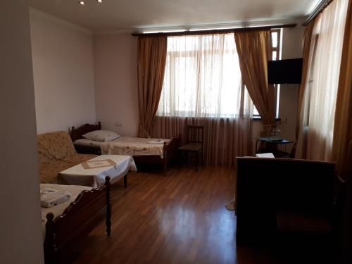 a room with two beds and a couch and a window at Hotel VIVAS in Goris