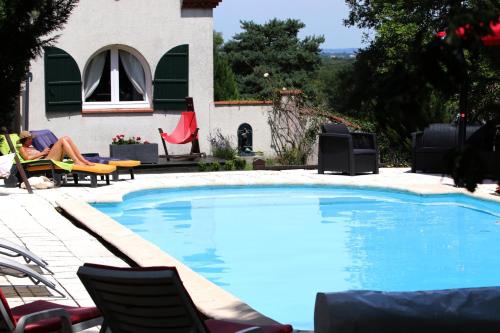 a woman sitting in a chair next to a swimming pool at Le Domaine du Vert bois in Pibrac