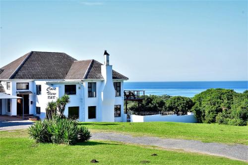 a white house with the ocean in the background at Cove View B&B in East London