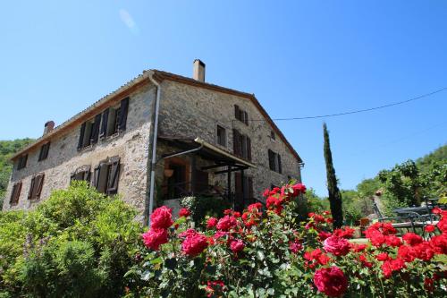 an old stone building with red roses in front of it at Mas Manyaques in Le Tech