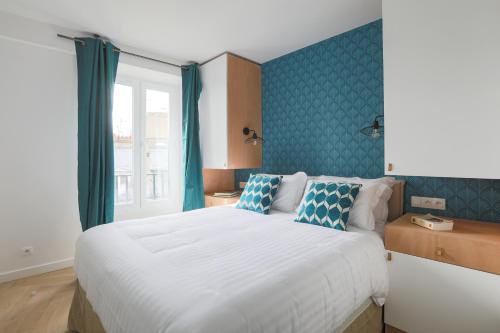 um quarto com uma grande cama branca com paredes azuis em LE MATISSIA em Paris