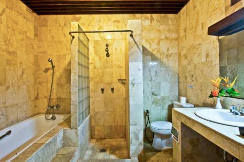 uma casa de banho com uma banheira, um WC e um lavatório. em Palm Garden Hotel em Sanur