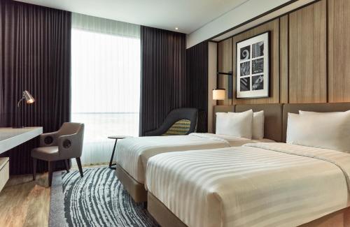 a hotel room with two beds and a desk at Novotel Karawang in Karawang