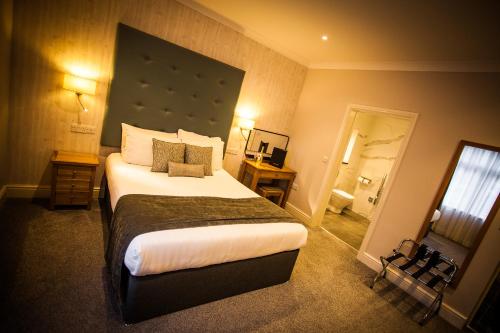 a bedroom with a large bed with a large headboard at Heywood Spa Hotel in Tenby
