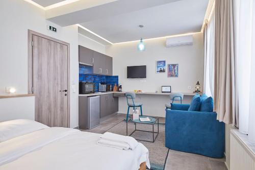 a bedroom with a bed and a blue chair and a kitchen at Live in a funky & renovated studio near Acropolis in Athens