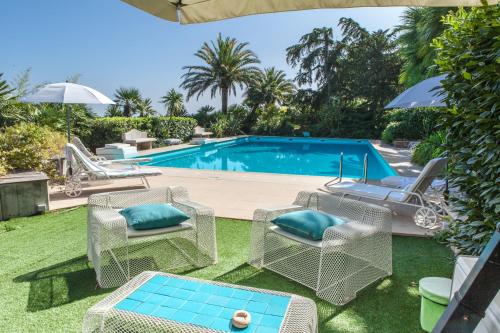 un patio trasero con piscina, sillas y mesa en Villa Capodarco B&B, en Porto San Giorgio