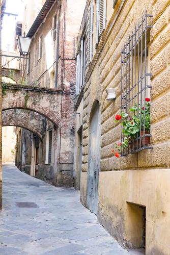 an alley with a building with flowers in a window at Albergo Tre Donzelle in Siena