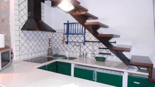 une cuisine avec des placards verts et un escalier en bois dans l'établissement Vivienda rural fuente de los gusarapos, à Burunchel