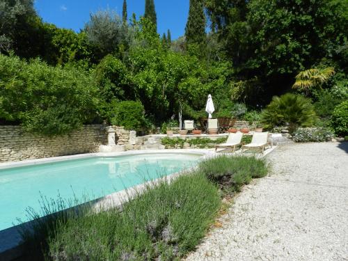 una piscina en un patio con 2 tumbonas en Les Acanthes en Lauris