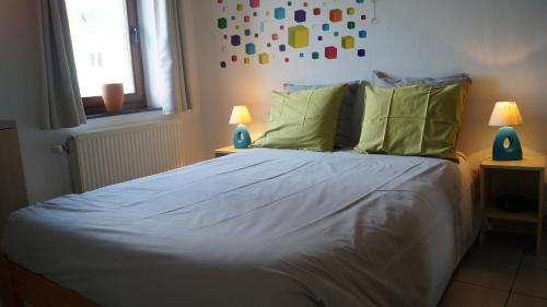 a bedroom with a bed with white sheets and green pillows at Gite Saboti in Dinant