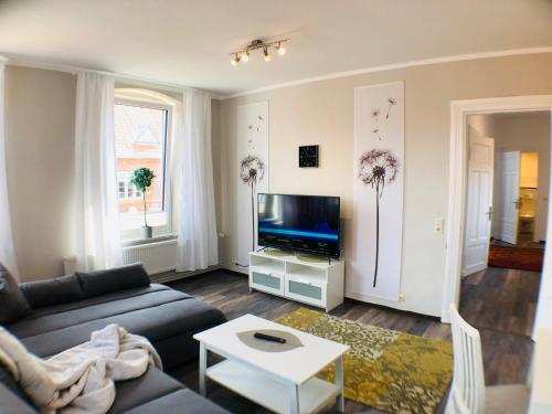 un salon avec un canapé et une télévision dans l'établissement Hafencity Apartments, à Tönning