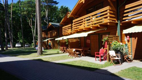 un bâtiment avec une table, des chaises et une terrasse dans l'établissement NATURA PARK Ustronie Morskie - domki, apartamenty, à Ustronie Morskie