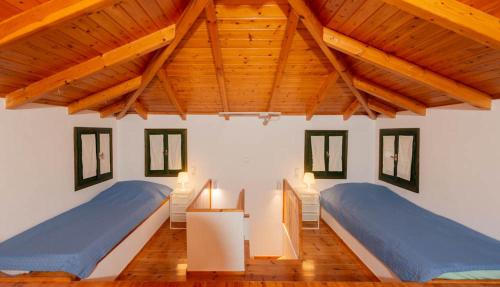 two beds in a room with wooden ceilings at Ionian Seaview apartments in Syvota