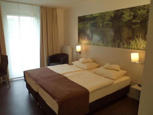 a bedroom with a bed with a large painting on the wall at Das Neue Hotel Am Park in Fröndenberg