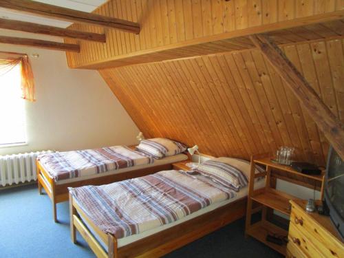 two beds in a room with wooden walls at Pension Sabine in Lützen