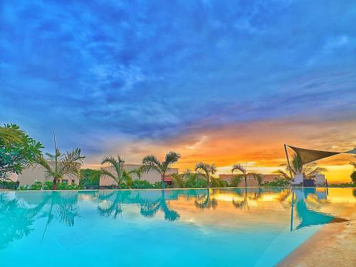 a large swimming pool with a sunset in the background at Vipingo Ridge-Swahili Villa in Mombasa