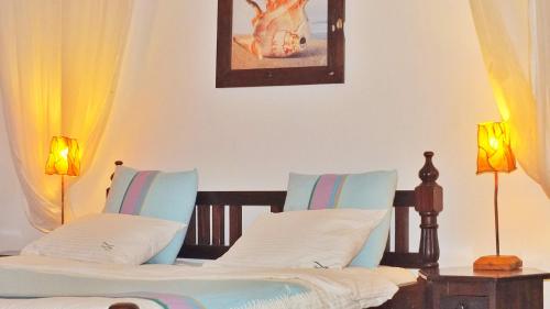 a bedroom with two beds with two lamps and a picture on the wall at Vipingo Ridge-Swahili Villa in Mombasa